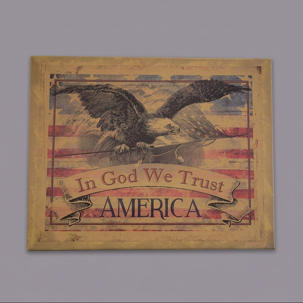 Decorative sign with an eagle, American flag, and 'In God We Trust' text on a wooden surface.