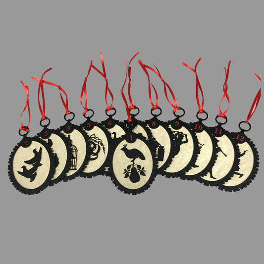 A set of twelve circular silhouette ornaments with red ribbons and black backgrounds, featuring various designs such as a partridge in a pear tree and the text '12 DAYS'.