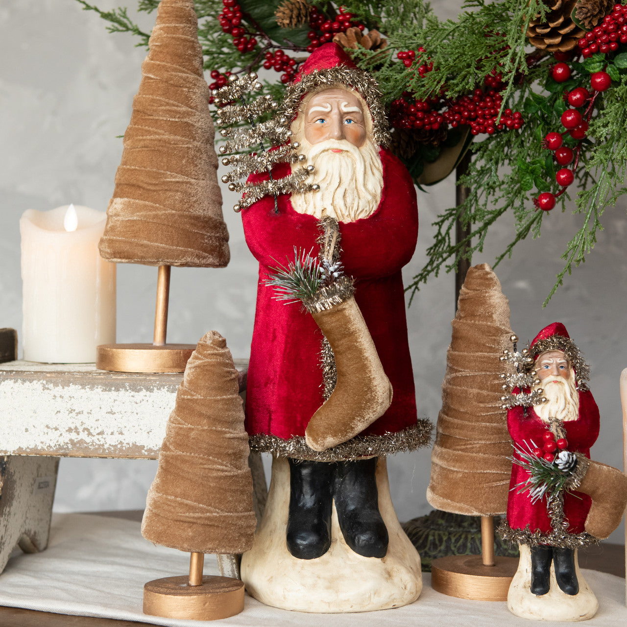 A 16.5 inch tall wine velvet belsnickel figurine, depicting a Santa-like character, with a red jacket, white beard, and a brown belt, standing next to a decorative tree.