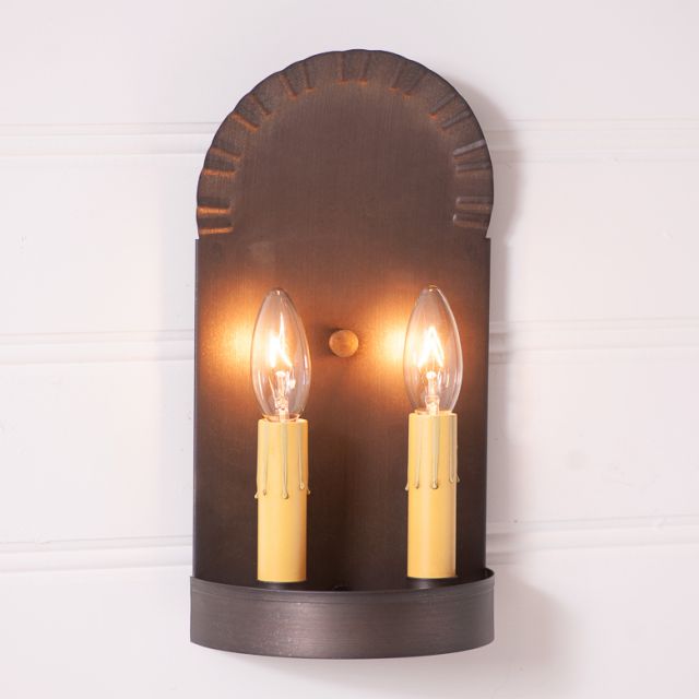 Wall-mounted sconce with two lit candles on a white background