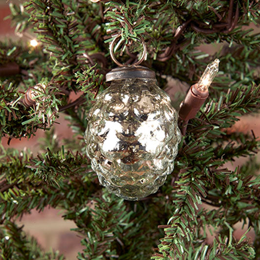A silver pine cone-shaped ornament hanging from a tree, with a reflective surface and visible wiring for lighting.