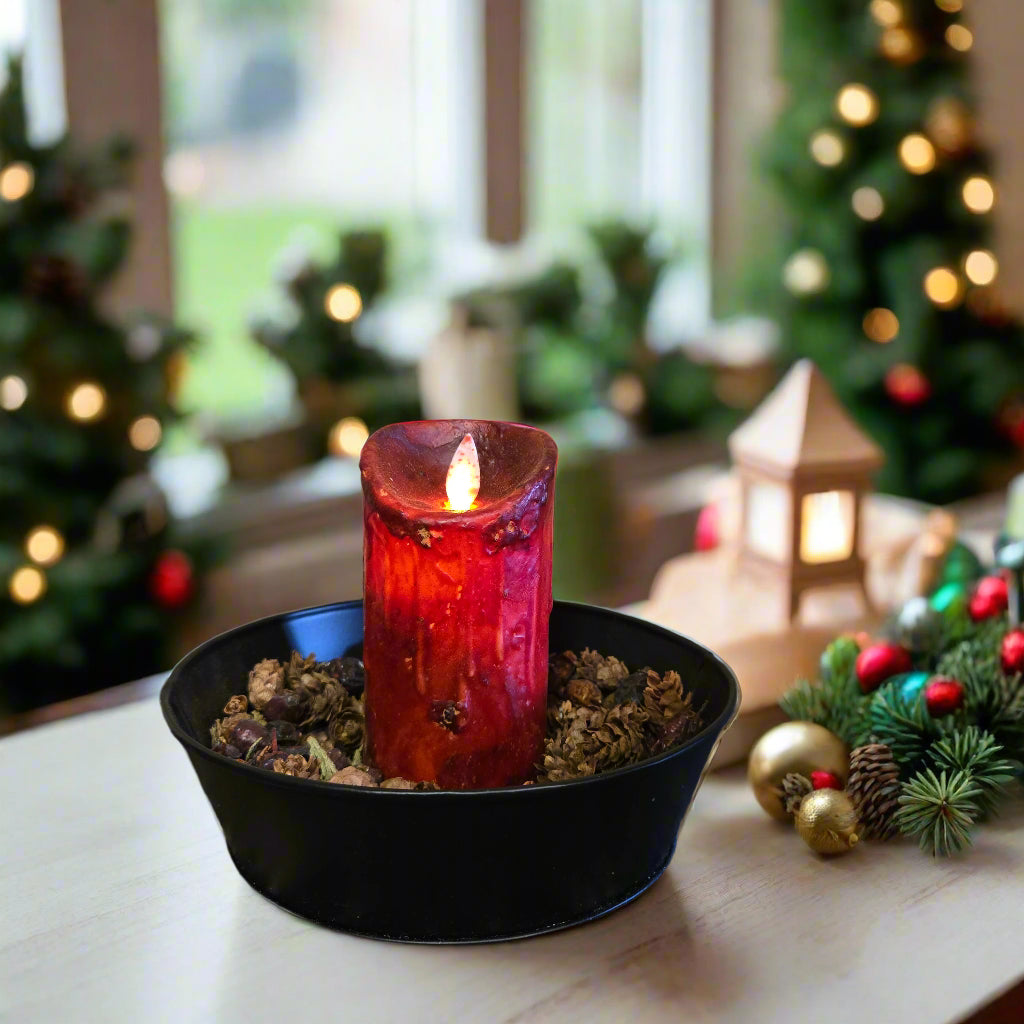 A burgundy colored LED candle with a moving flame effect, placed in a black holder on a patterned surface.