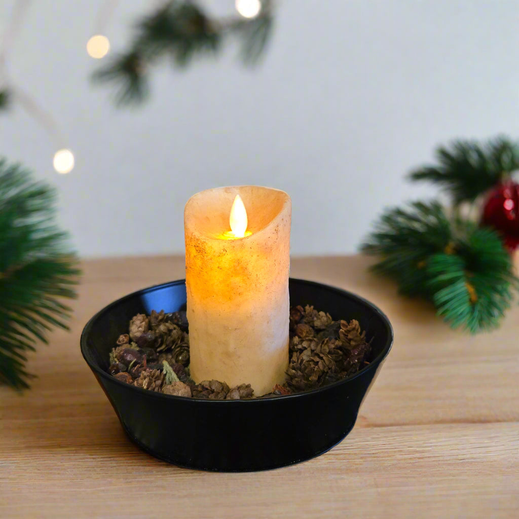 An LED candle with a moving flame effect, placed in a black holder on a textured mat, depicting a burnt ivory color.