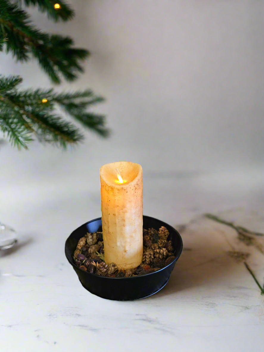 A flameless ivory pillar candle with a moving flame effect, displayed against an rustic background.