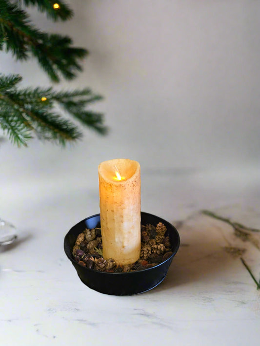 A flameless ivory pillar candle with a moving flame effect, displayed against an rustic background.