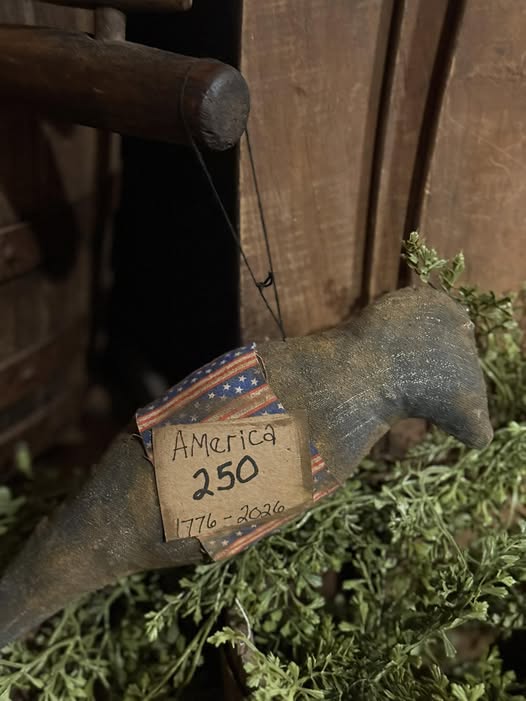 Decorative crow ornament with 'America 250' label on a wooden background