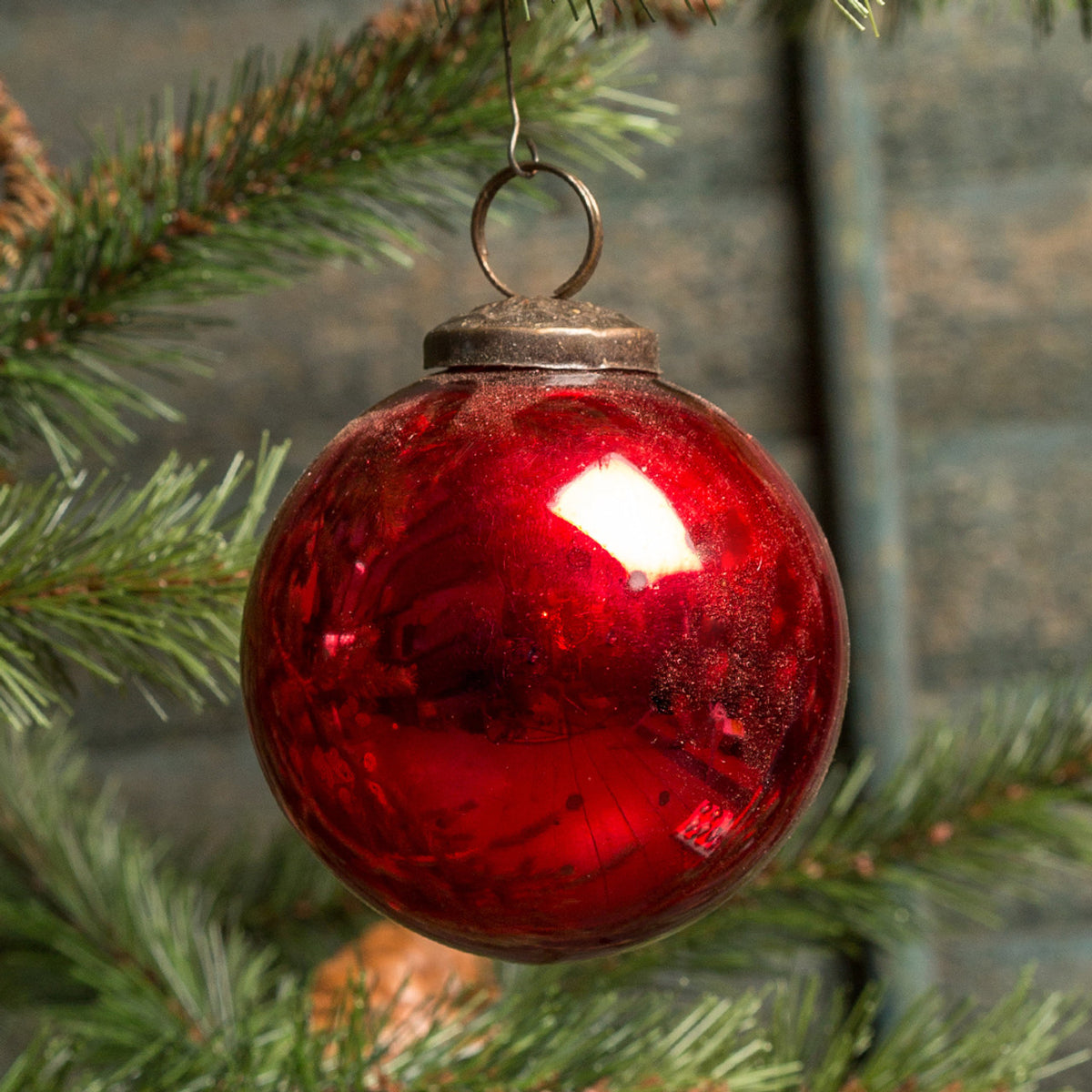 Red glass ornament hanging on a Christmas tree branch