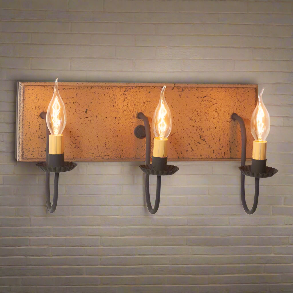 A pearwood painted wooden vanity light with black textured arms and three E12/Candelabra sockets with visible bulbs.