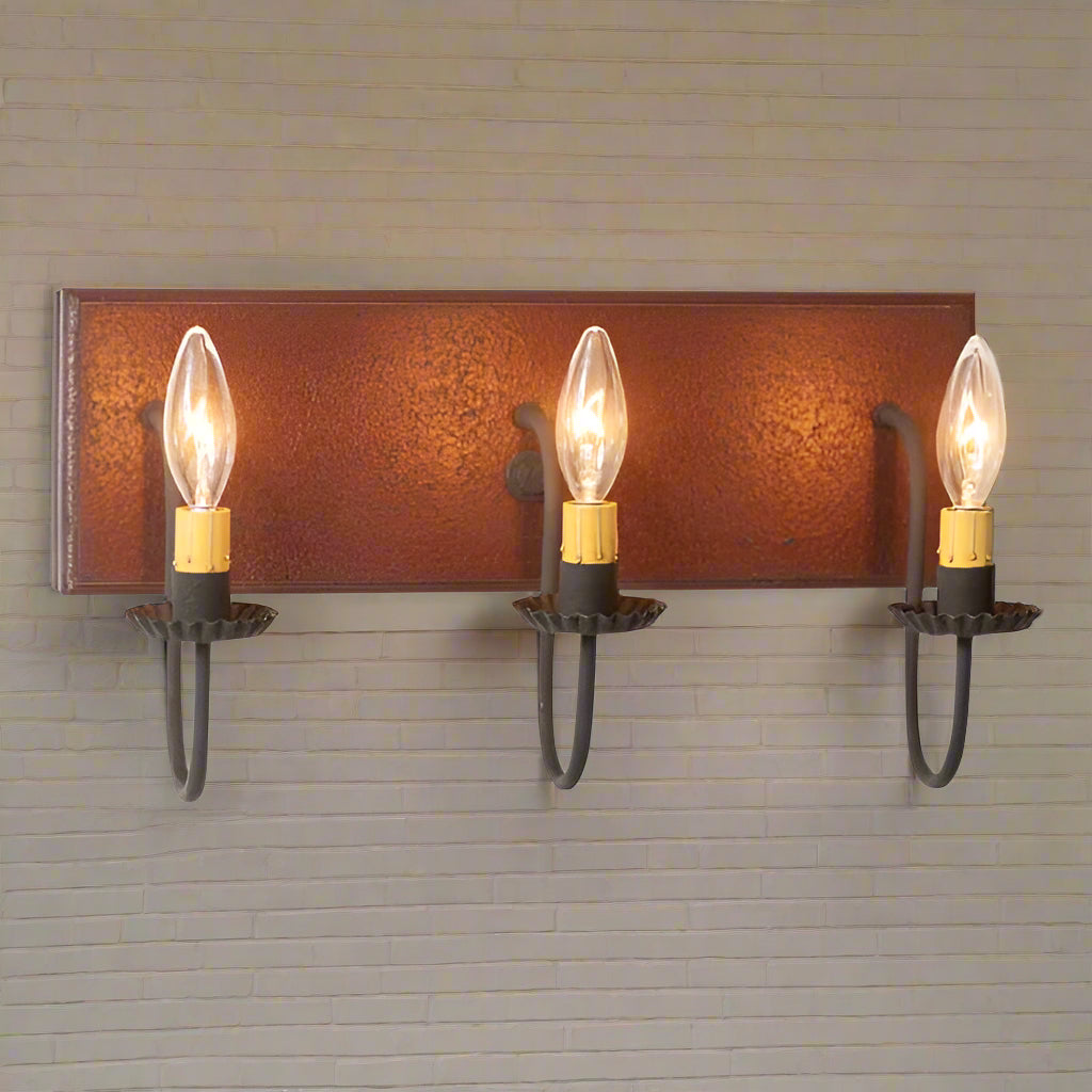 A plantation red vanity light with three bulb holders and black textured arms, against a white background.