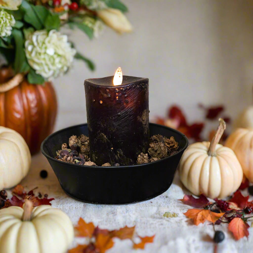 A black moving flame pillar candle on a rustic background