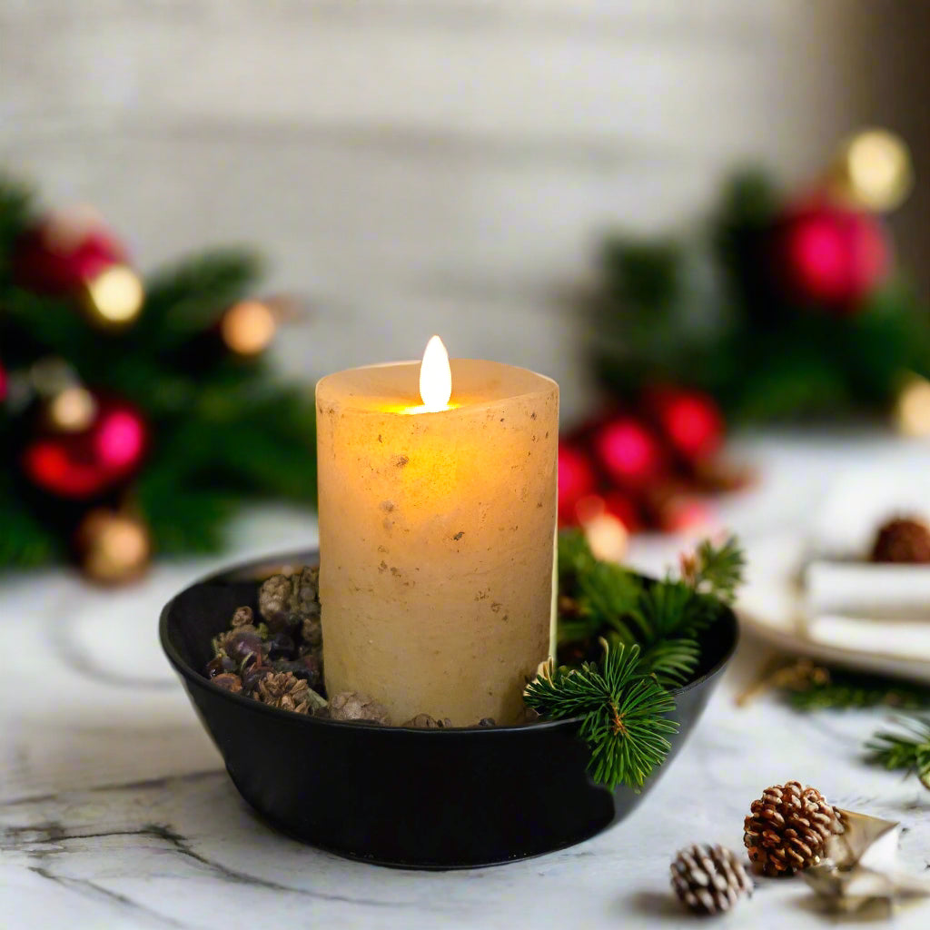 A 3 inch by 4 inch moving flame pillar candle in burnt ivory color, placed in a black holder with a timer feature.