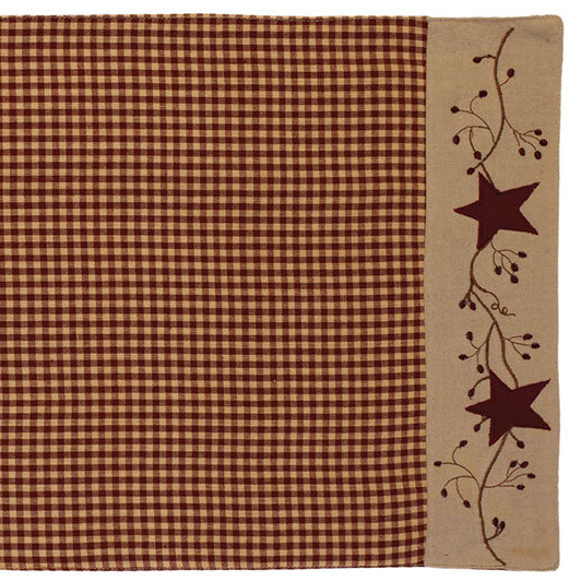A burgundy table runner with a star and berry design, featuring a checkered pattern on the stars.