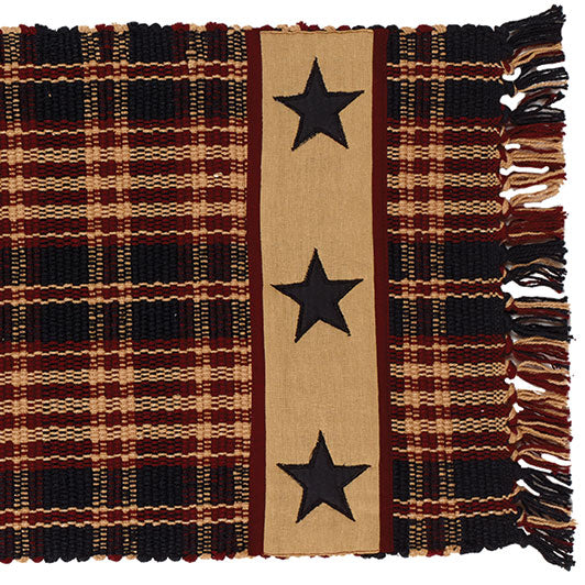 A 36-inch Village Star Runner with a geometric star design on a plaid background with brown and black fringed ends.