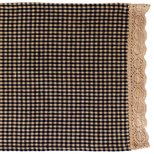 A checkered table runner with black and white squares and a lace-like border at the bottom corner.