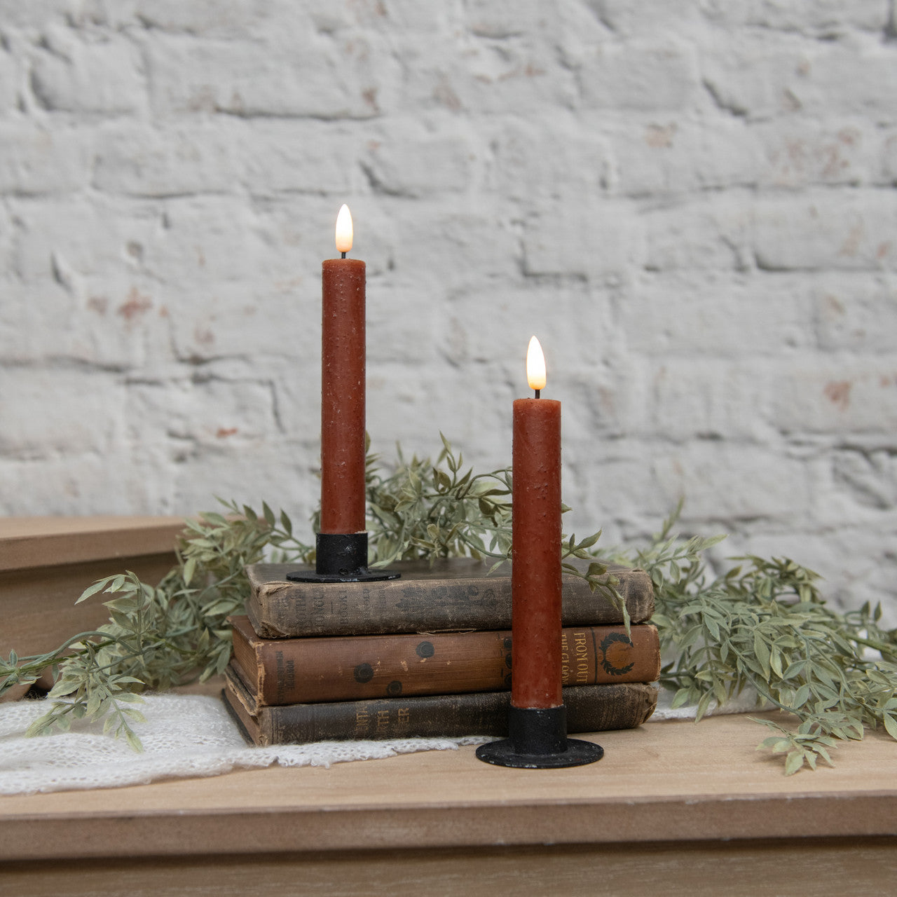 Two lit candles on stacked books with a rustic background