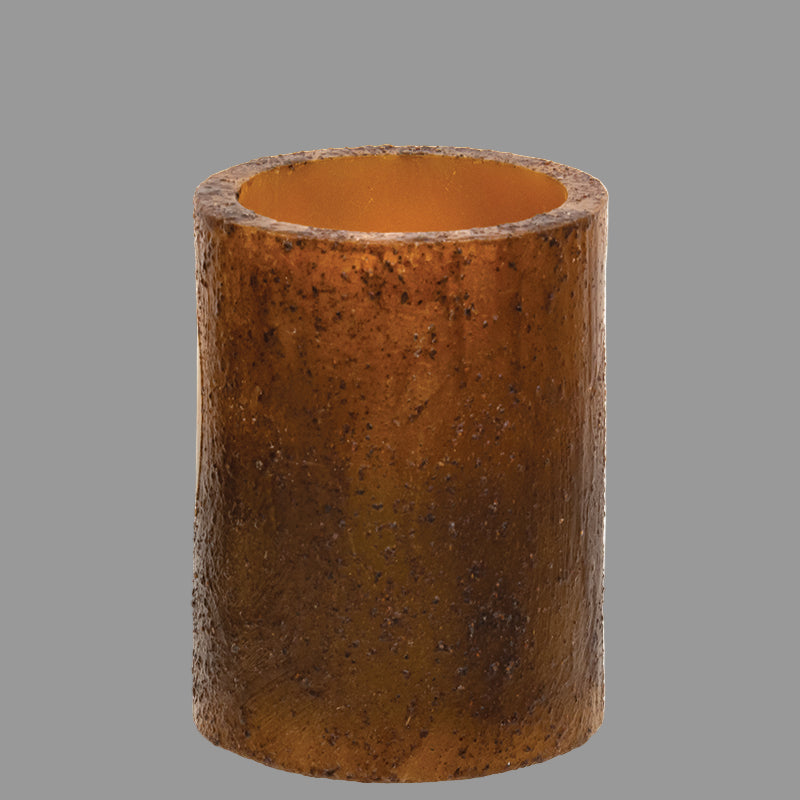 A cylindrical burnt mustard colored candle pillar with a textured wax coating.