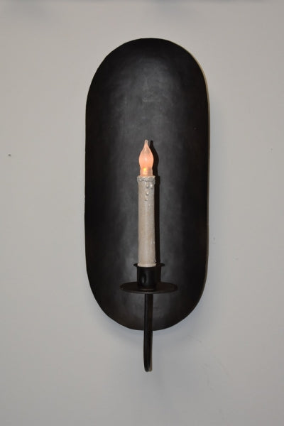 Black metal wall sconce with a matte finish, designed to hold a taper candle, shown with a candle lit.