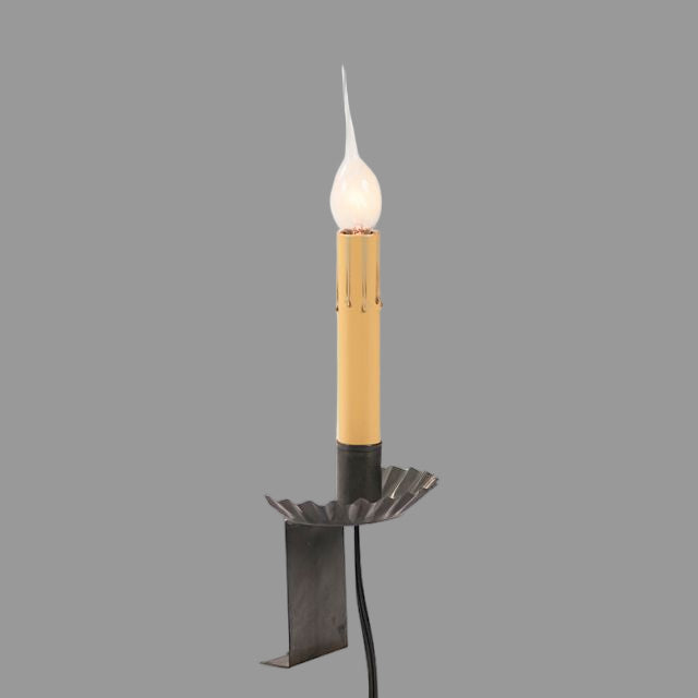 A black window sill light with a candle-like appearance, featuring a lit tip, with a visible power cord.