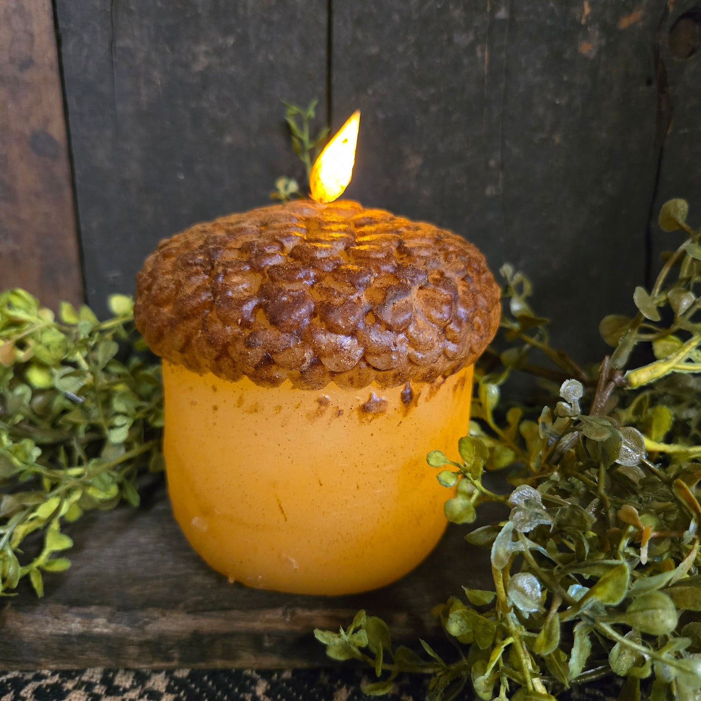 Decorative acorn with a battery operated candle inside on a wooden background