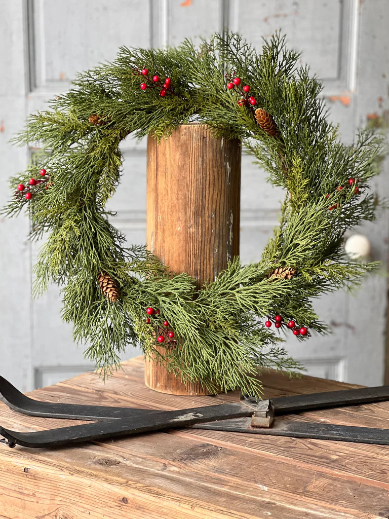 Wreath with alpine and berries with white wooden door in background.