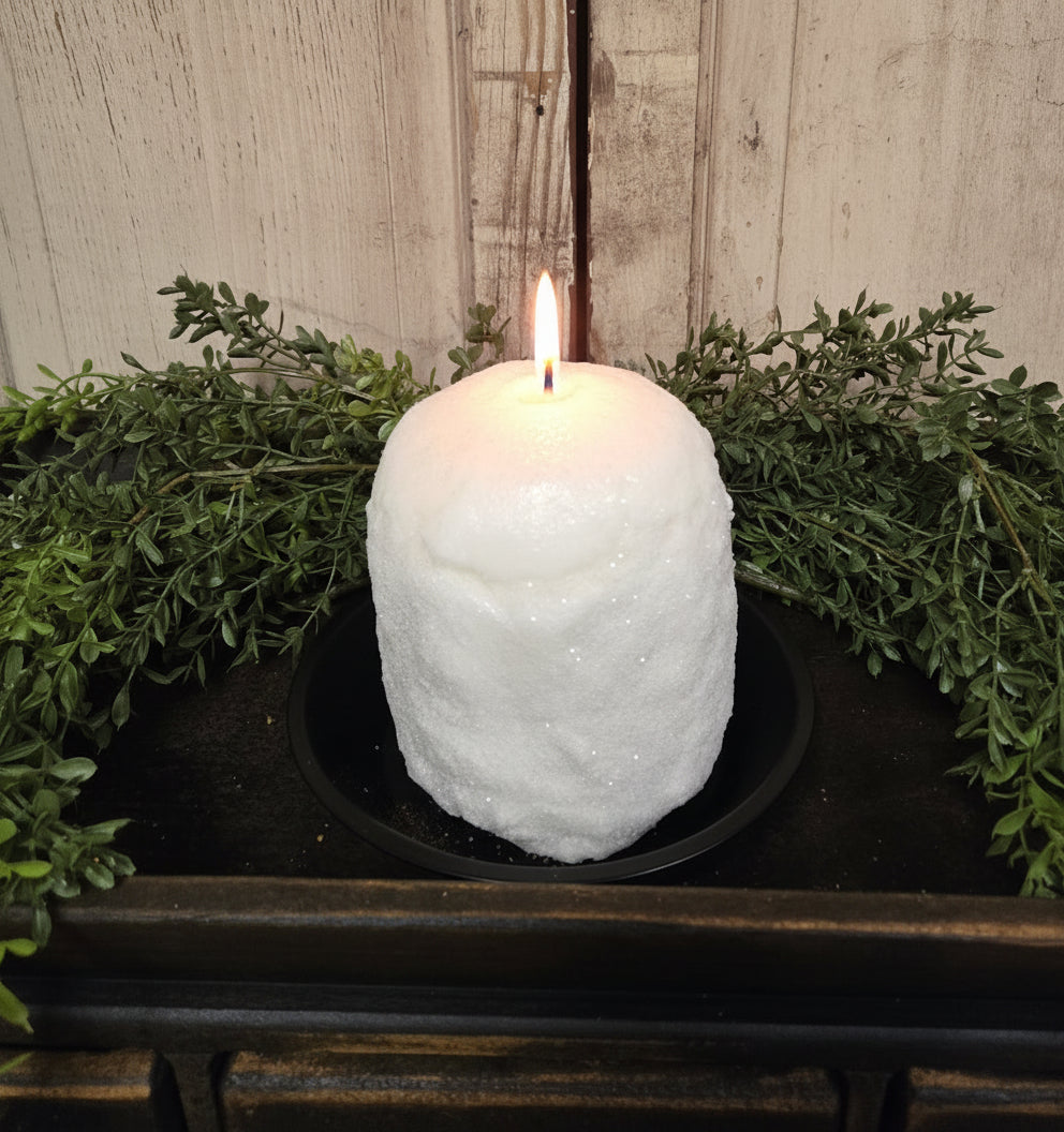 Glittered candle sitting on wood tray with herb greenery