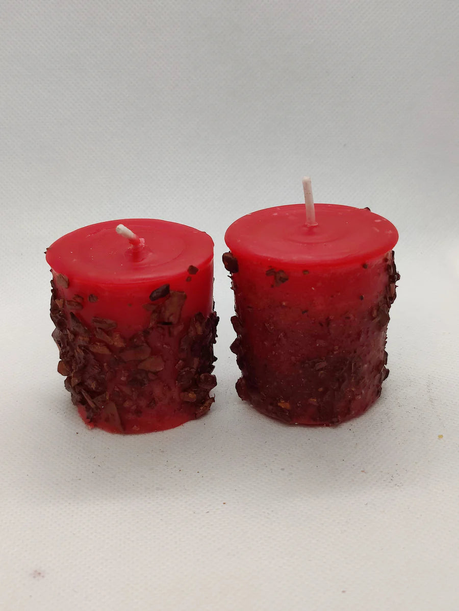 Two red scented votive candles with visible wicks, placed on a white background.