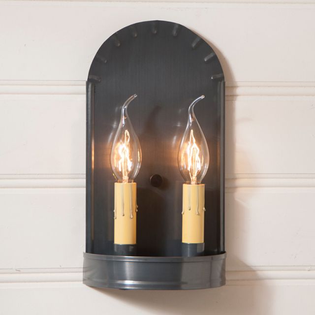 Wall-mounted light fixture with two lit bulbs on a white wall background