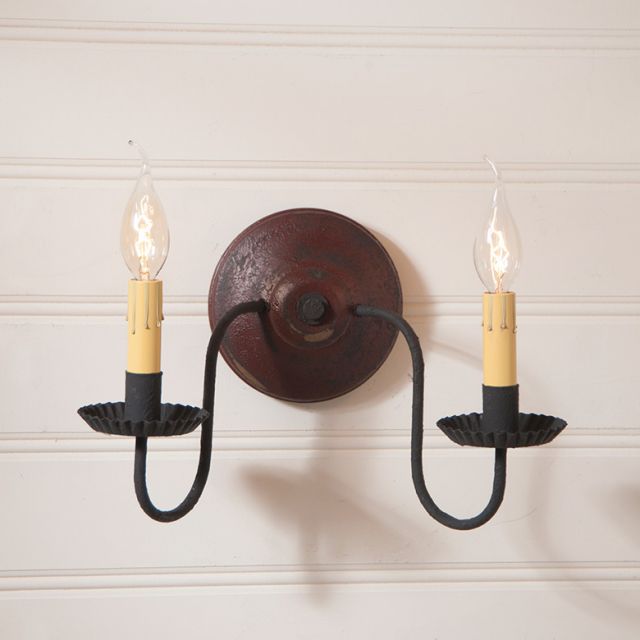Wall-mounted light fixture with two candles on a white wall