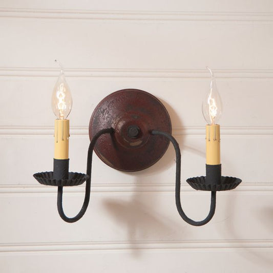 Wall-mounted light fixture with two candles on a white wall