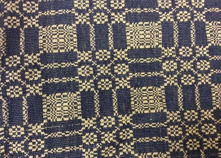 Close-up view of a navy table runner with a geometric autumn frost weave pattern.