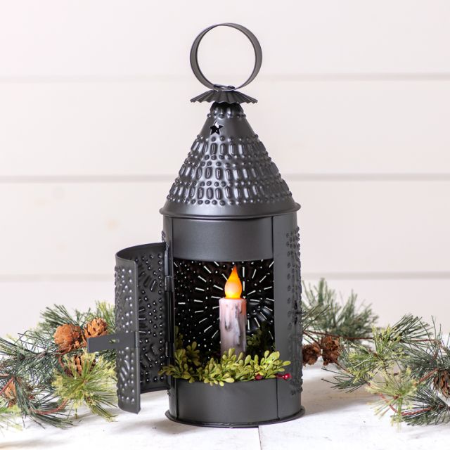 Decorative black lantern with a candle inside, surrounded by Christmas decorations on a white background