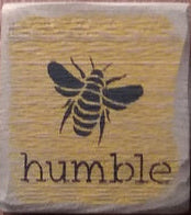 A rectangular wooden sign with a yellow background, featuring a black bee illustration and the word 'Humble' on it.