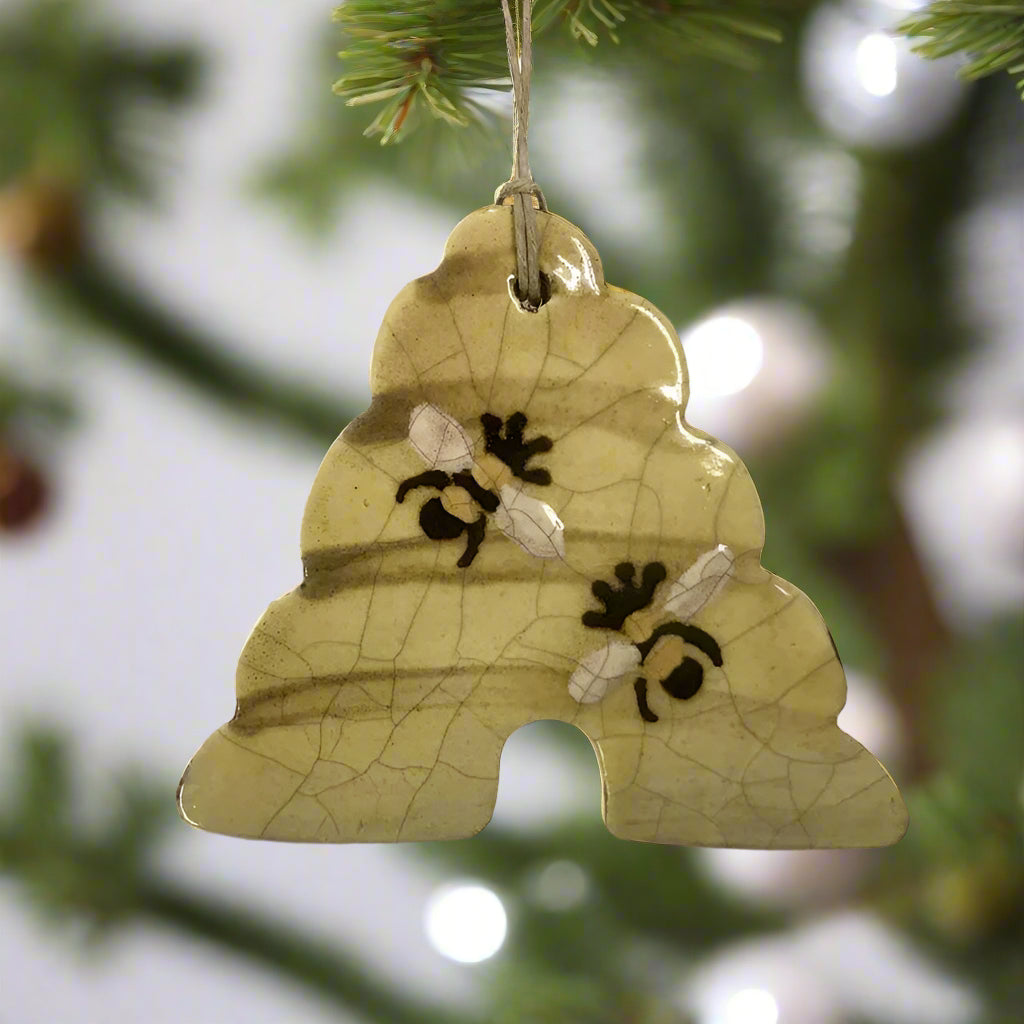 A handcrafted redware ornament featuring a yellow bee skep, with a crackled glaze.