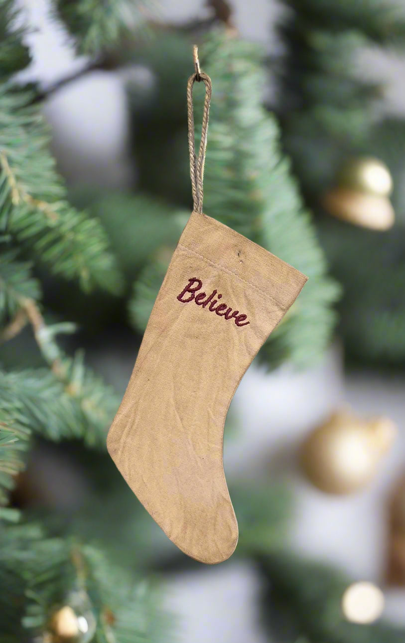Stocking with word "believe" hanging from a Christmas tree