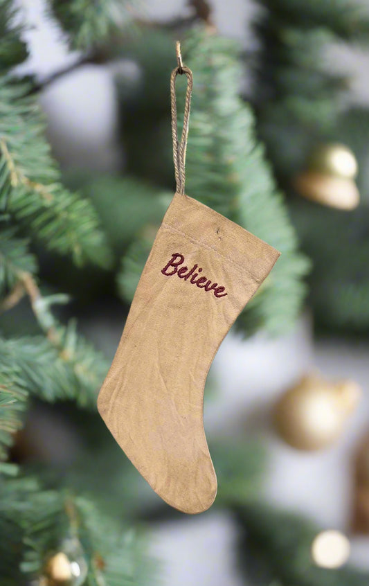 Stocking with word "believe" hanging from a Christmas tree