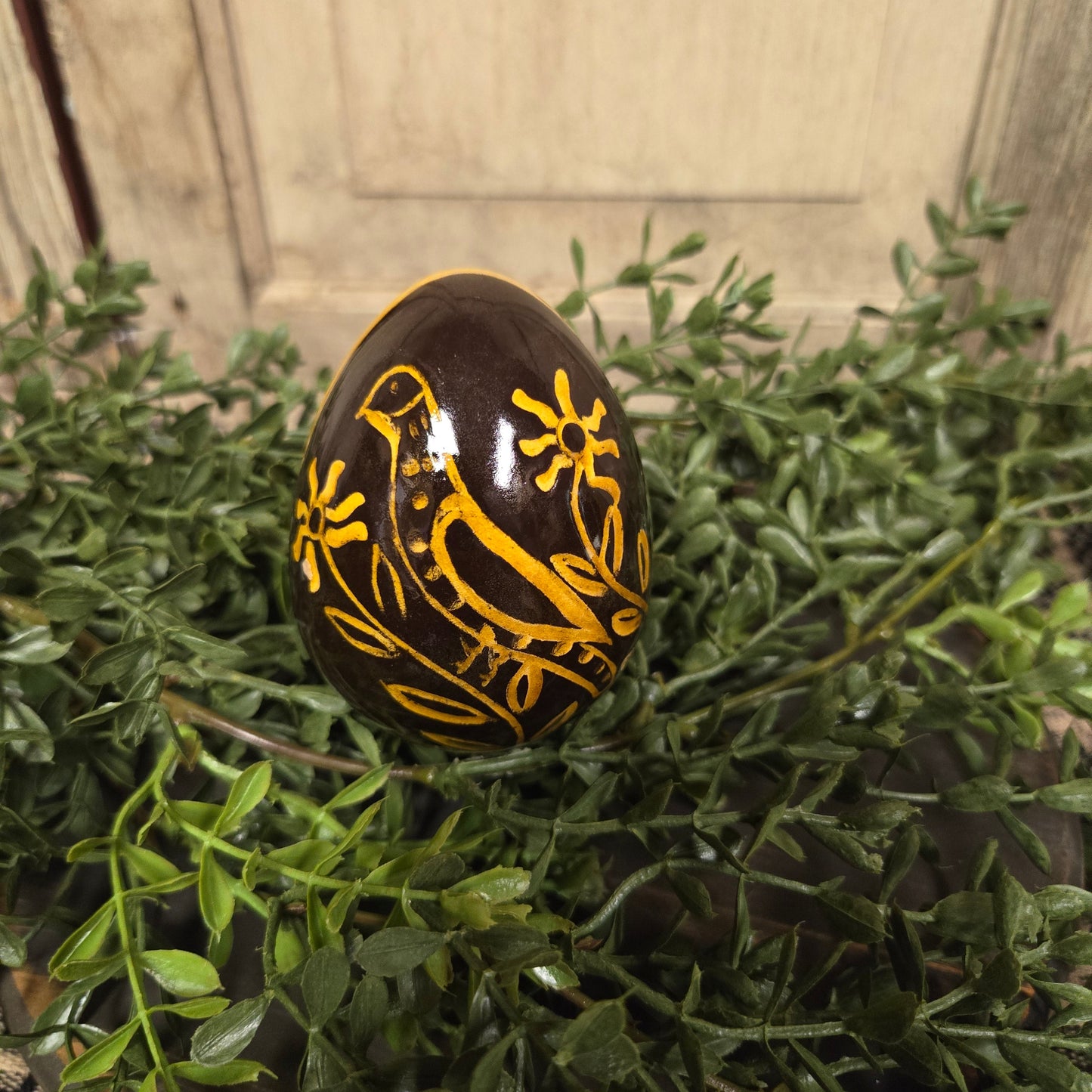 Brown redware egg with yellow glazed bird and flowers