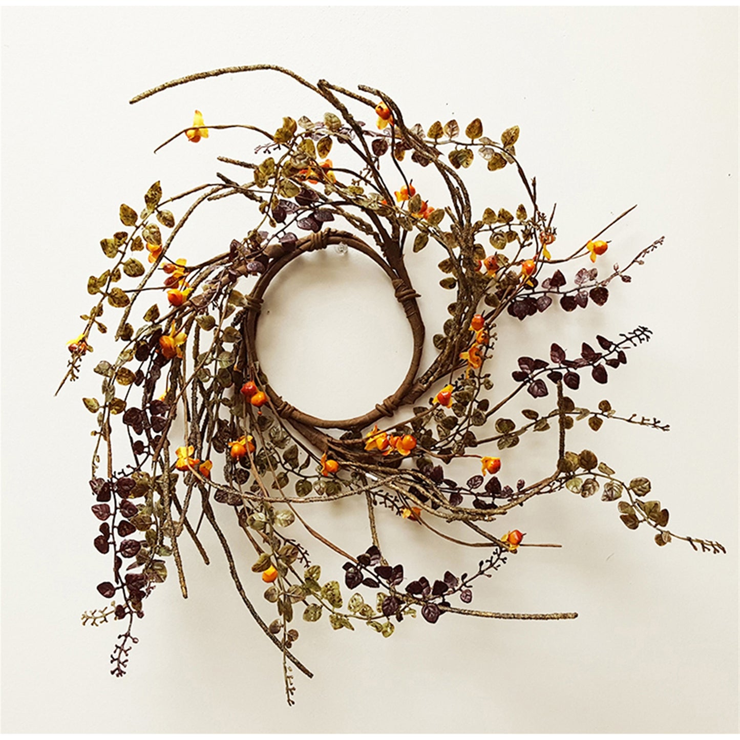 A brown candle ring with green leaves and orange berries.