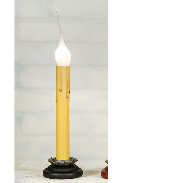 Black base window candle with cream sleeve and a silicone candelabra bulb show on a window sill with greenery beside it