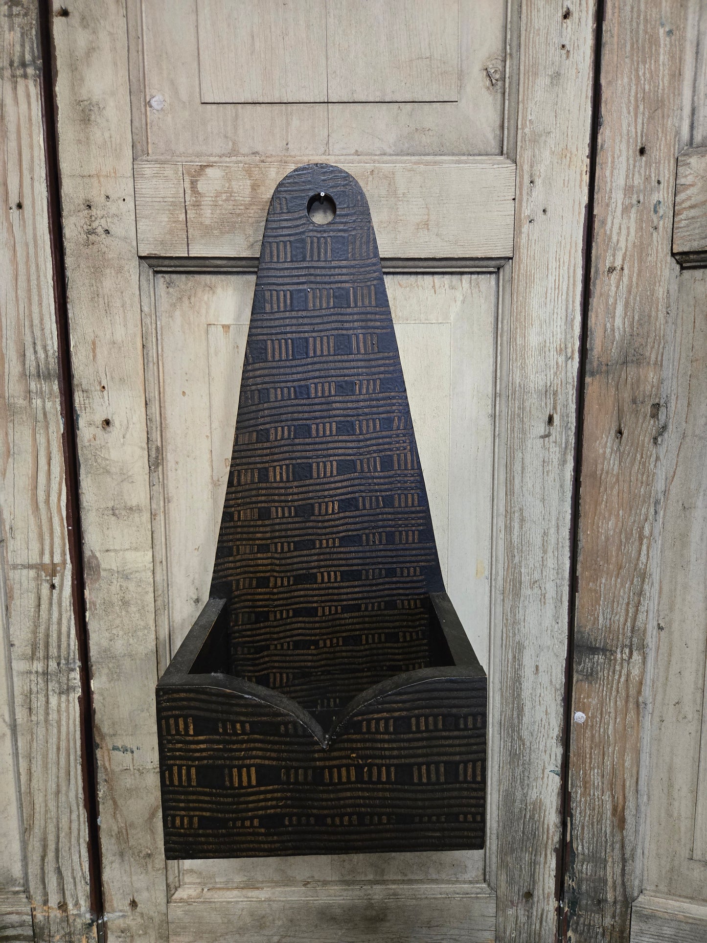 Black sconce box with a painted combed pattern on a wooden surface