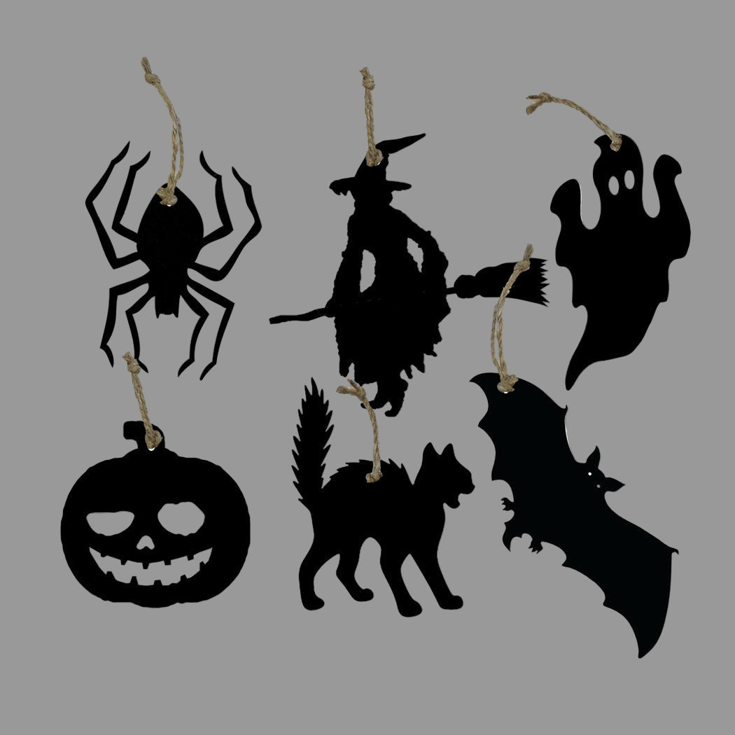 A collection of black, wooden silhouette ornaments for Halloween, including shapes of a spider, witch, pumpkin, bat, and ghost, with twine hangers.