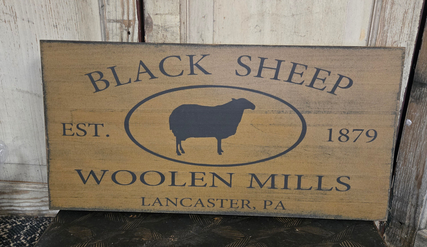 Wooden sign with 'Black Sheep Woolen Mills' branding on a rustic background