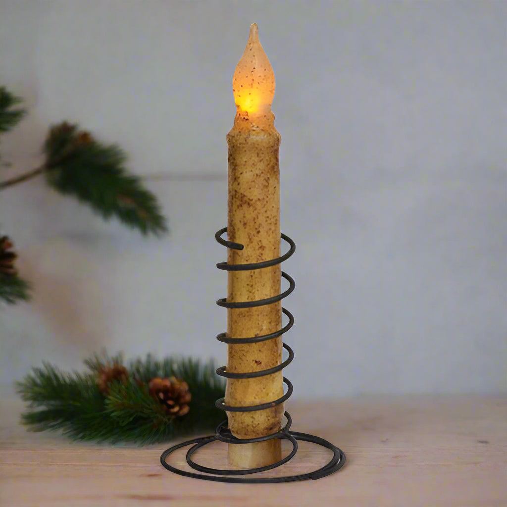 Decorative candle with spiral design and glowing flame on a white background