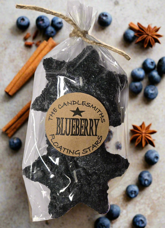 A pack of two blueberry-scented floating candles, shaped like stars, wrapped in clear plastic packaging with a label that reads 'The Candlesmith Blueberry'.