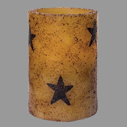 A cylindrical pillar candle with a burnt ivory color and multiple black stars pattern on it.