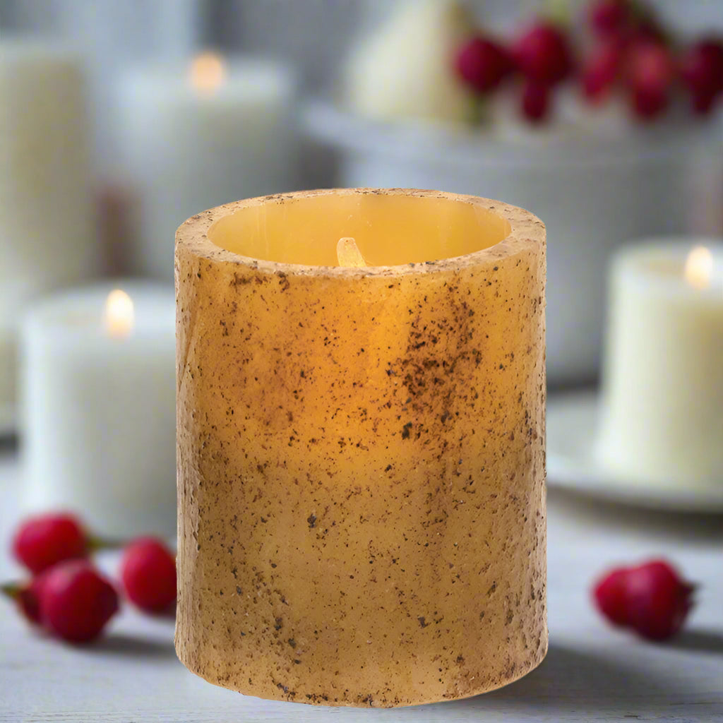 A burnt ivory colored LED pillar candle with a real wax candle sleeve and a grungy cinnamon coating, devoid of flames.