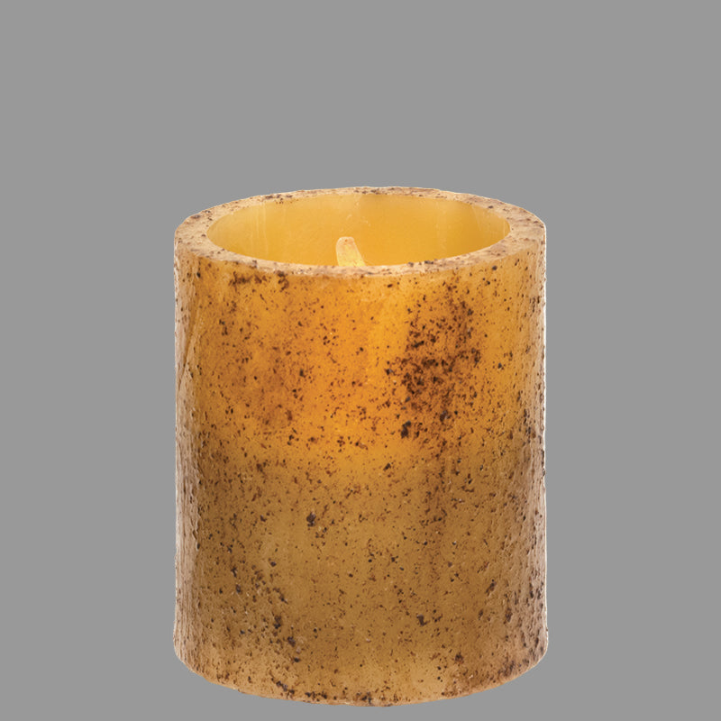 A burnt ivory colored LED pillar candle with a real wax candle sleeve and a grungy cinnamon coating, devoid of flames.