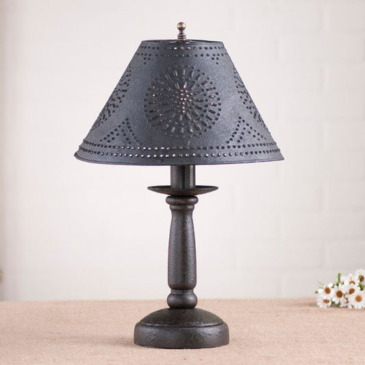 Decorative table lamp with a black pierced shade and wooden base on a neutral background