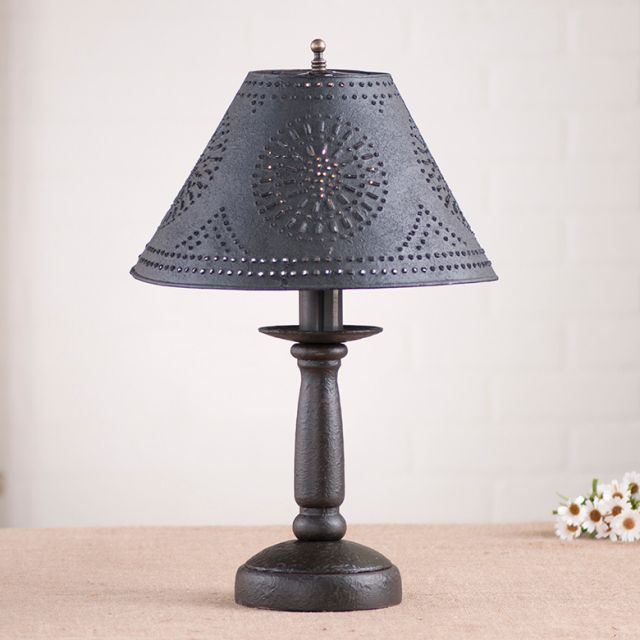 Decorative table lamp with a black pierced shade and wooden base on a neutral background