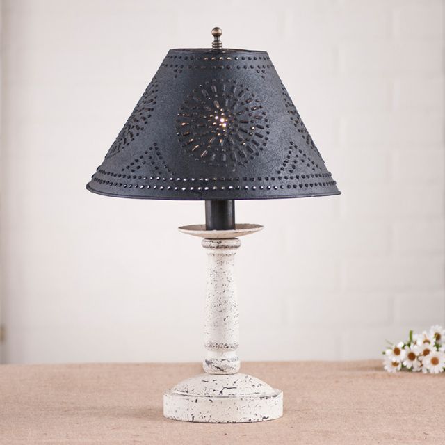 Table lamp with black perforated shade and white base on a neutral background
