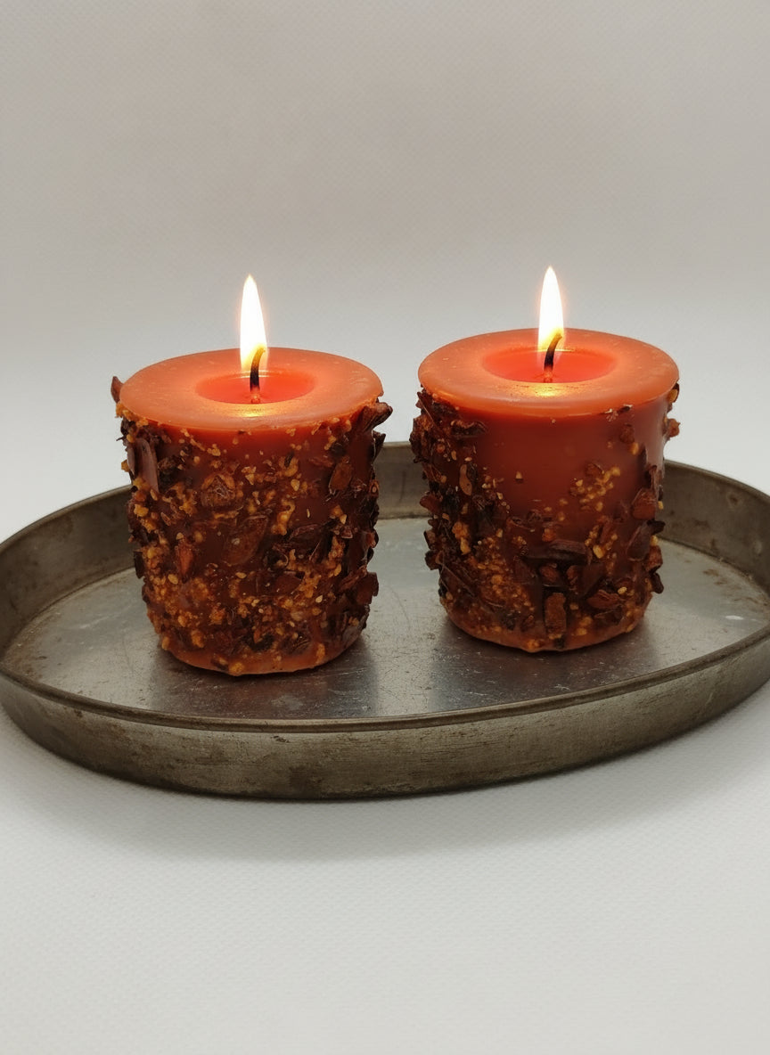 Two rustic candles with textured bases on a plain background